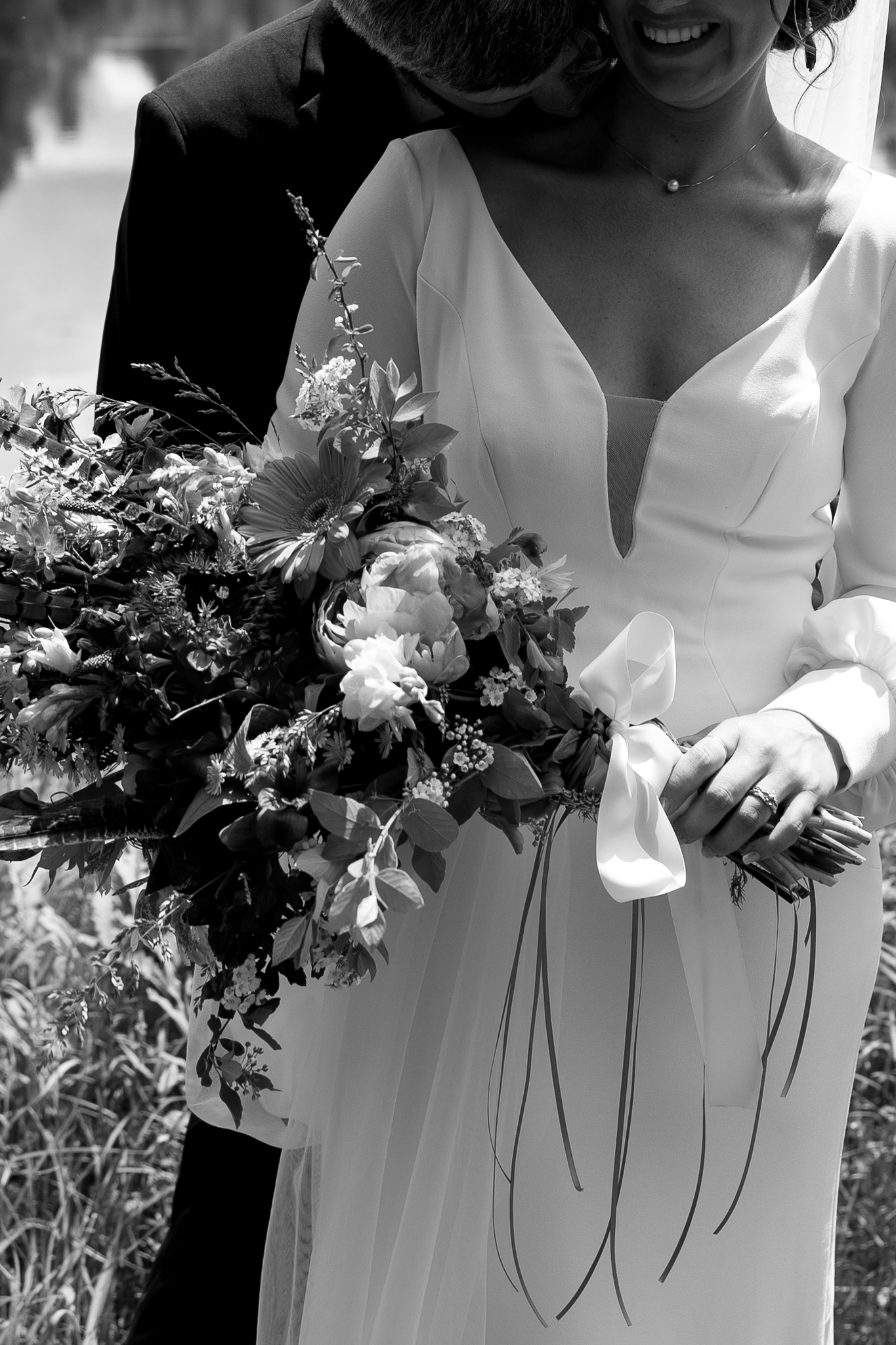 New England Coastal Elopement | Sincerely Liz Photography Vermont Wedding Photographer | A bride in a V-neck gown holds a bouquet of flowers. The black-and-white image captures an intimate moment, exuding joy and elegance.