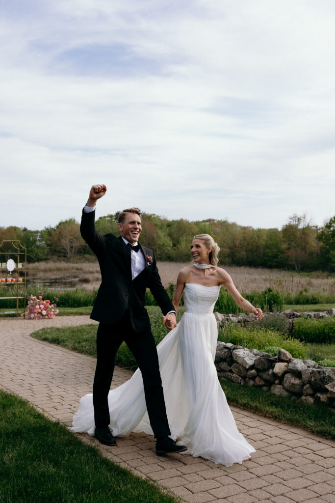 The couple walks hand in hand across a garden path just after the ceremony, a joyful frame that fits wedding venues for 50 guests Vermont couples may consider.