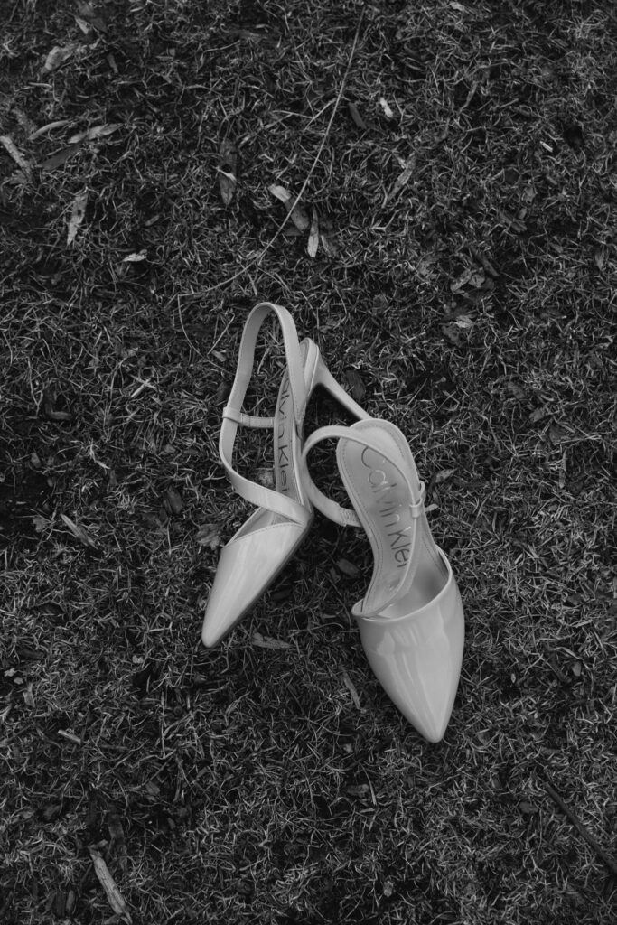 Boston Public Garden | Sincerely Liz Photography Documentary and Editorial Wedding Photography | Black and white image of elegant high-heeled shoes on grass. The scene conveys a sense of elegance and a serene, nostalgic mood.