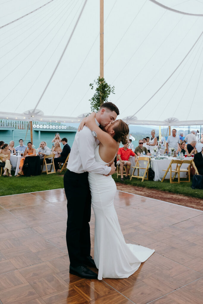 Wedding Photographers in Vermont | Sincerely Liz Photography Documentary and Editorial Wedding Photography | A couple shares a romantic first dance under a white tent at a wedding reception. Guests seated at tables watch, creating a joyful and celebratory atmosphere.