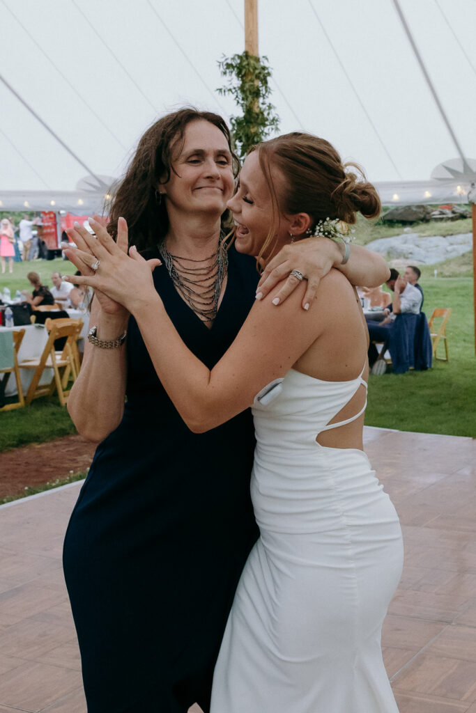 Bride embraces a guest on the dance floor beneath a tent as the celebration unfolds around them, the kind of heartfelt scene that defines small wedding venues in VT.