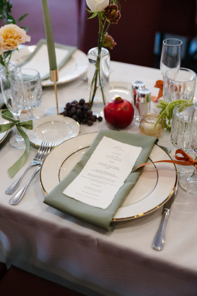 Reception table styled with layered textures, fruit accents, and elegant paper goods during an intimate dinner setup, reflecting the elevated details featured in Vermont wedding photography.