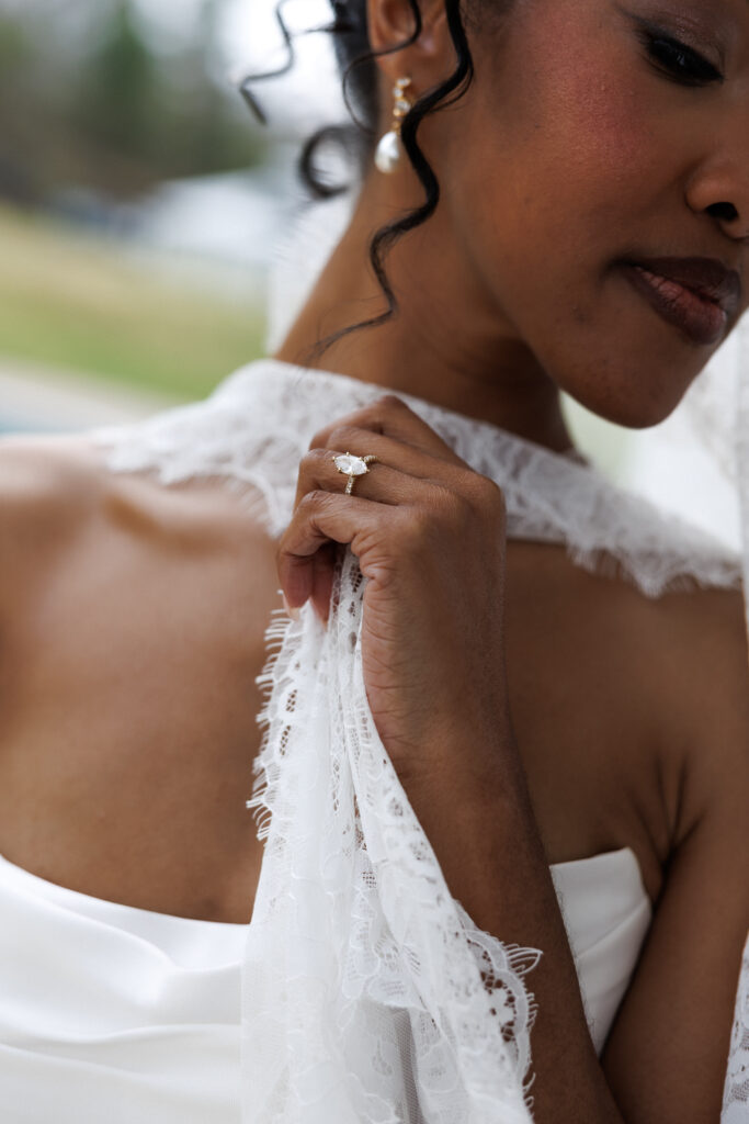 Close-up bridal portrait featuring textured lace gloves, soft curls, and delicate jewelry photographed with the timeless detail work associated with fine-art Massachusetts wedding photographers.
