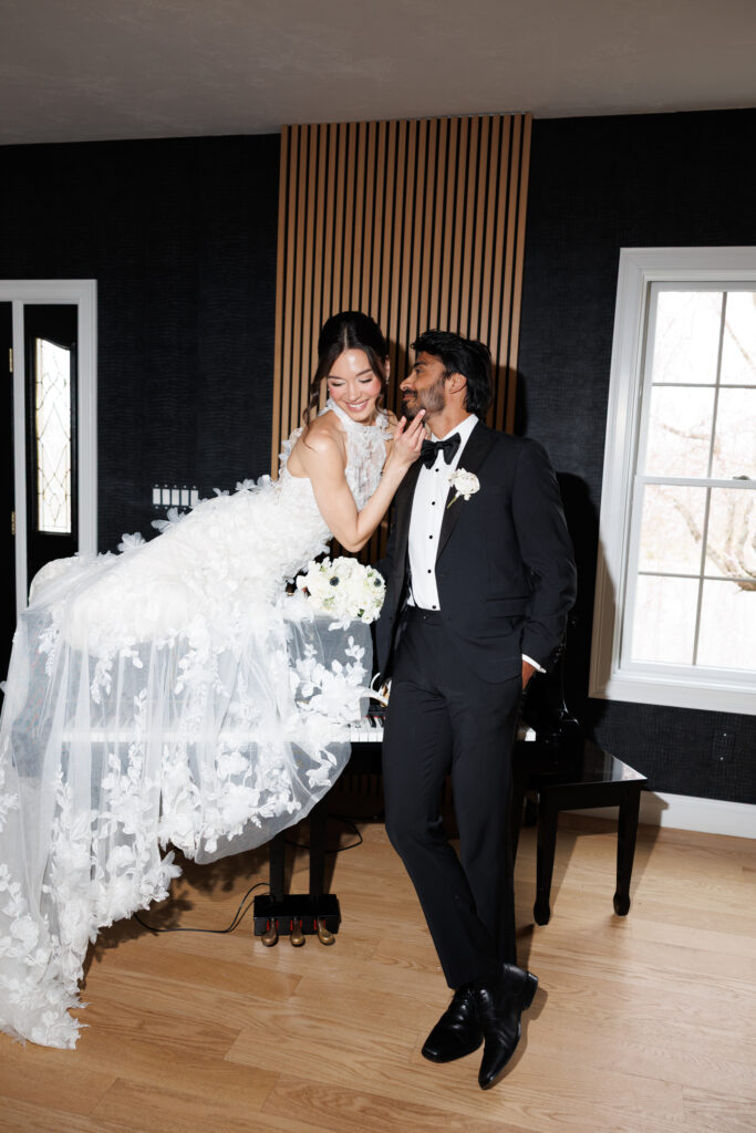 Couple laughs together indoors beside dramatic draping and a grand piano during an editorial-inspired wedding portrait session at The Hacienda, one of the more visually dynamic settings for wedding photography in Massachusetts.