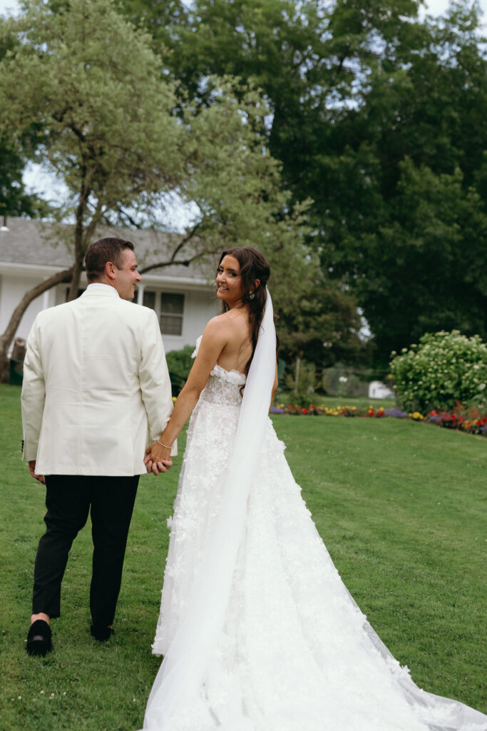 Bride and groom holding hands and smiling on the green lawns of Basin Harbor in Vermont
