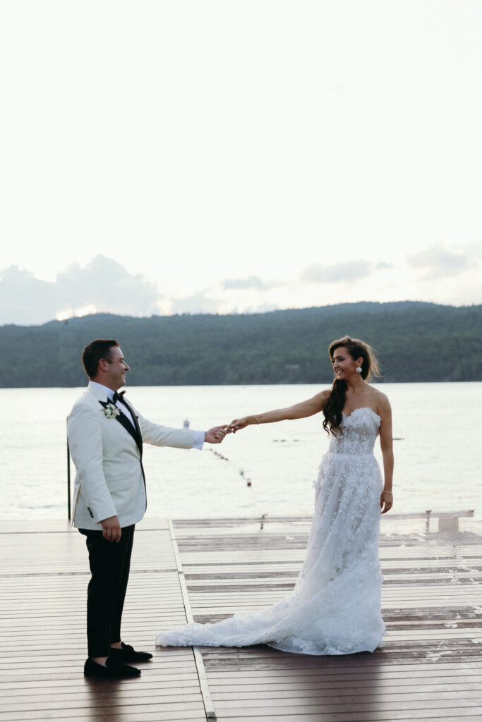 Bride and groom holding hands on a Lake Champlain dock, photographed during their Basin Harbor wedding
