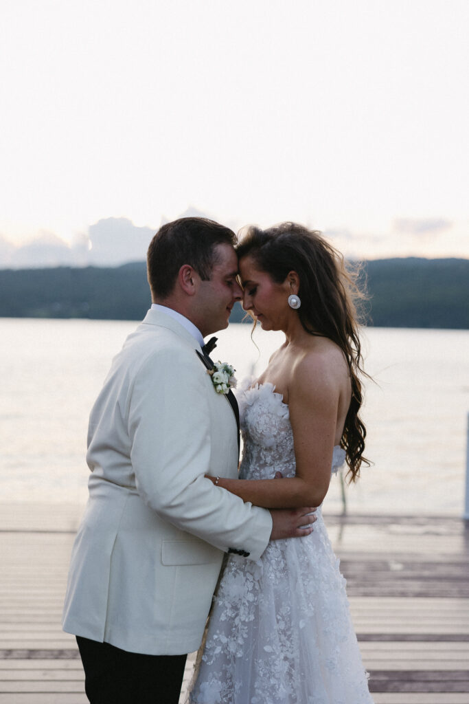 Newlyweds embracing on a dock overlooking Lake Champlain at their Basin Harbor wedding