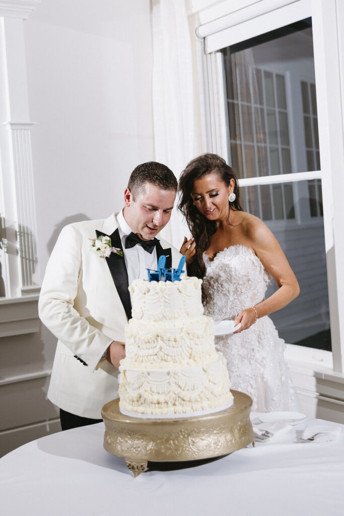 Newlyweds cutting a tiered white wedding cake during their Basin Harbor reception