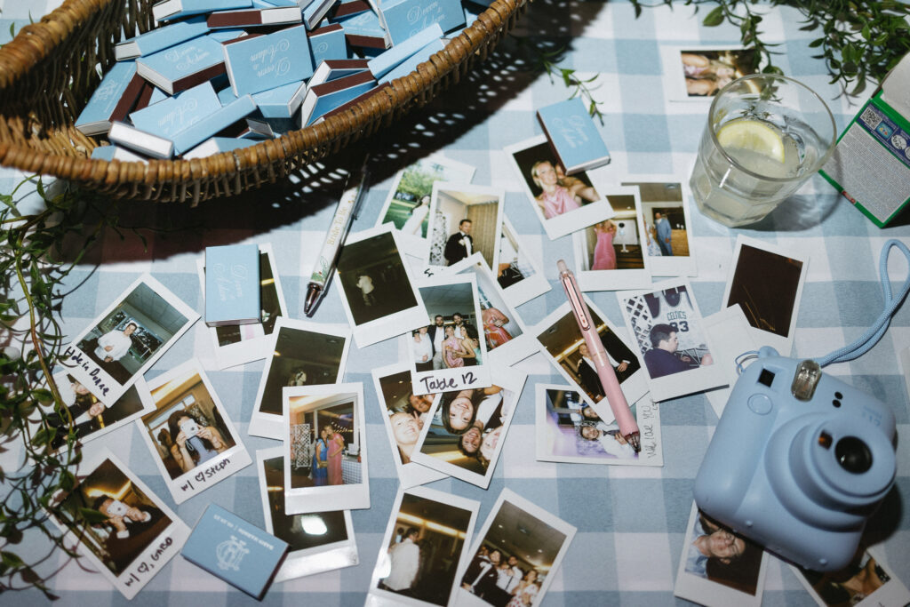 Blue wedding favor boxes and instant photographs displayed on a blue-and-white checkered tablecloth