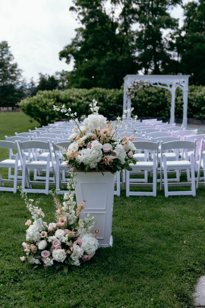 Basin Harbor wedding inspiration featuring blush, peach, and ivory floral arrangements along an outdoor ceremony aisle